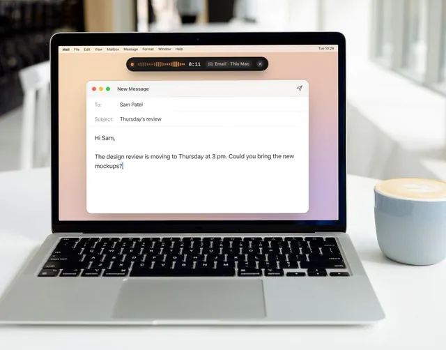 A MacBook on a white table next to a coffee. On the screen, an email is being written by voice, with Keyey’s dictation pill at the top.