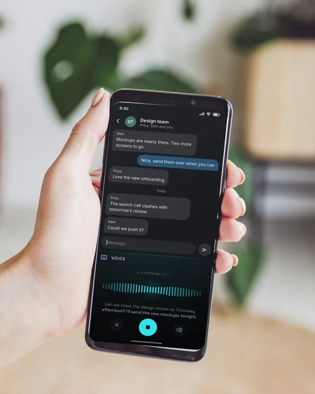 A hand holding an Android phone in a bright room with plants. On the screen, Keyey’s voice panel is typing a reply in a team chat.